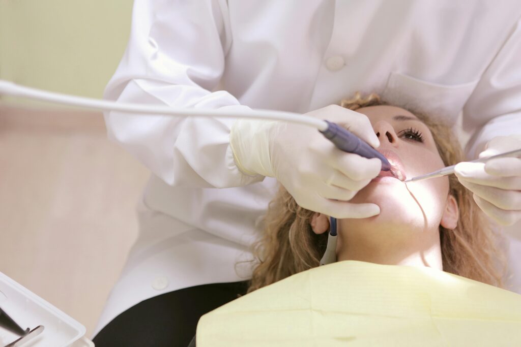 A dentist performing a dental procedure on a reclining female patient in a modern clinic.